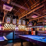 Interior of the Roxy Ball Room with bright neon lights, a bar and gaming tables.