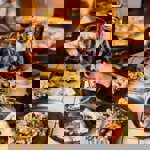 A table in a restaurant is laid out with a sumptuous meal. Two hands, from each side of the table, are holding glasses of red wine. 