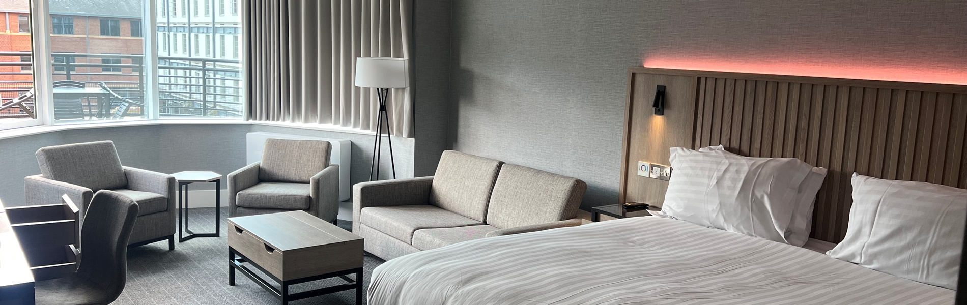 Modern double bedroom with seating area and ambient mood lighting.