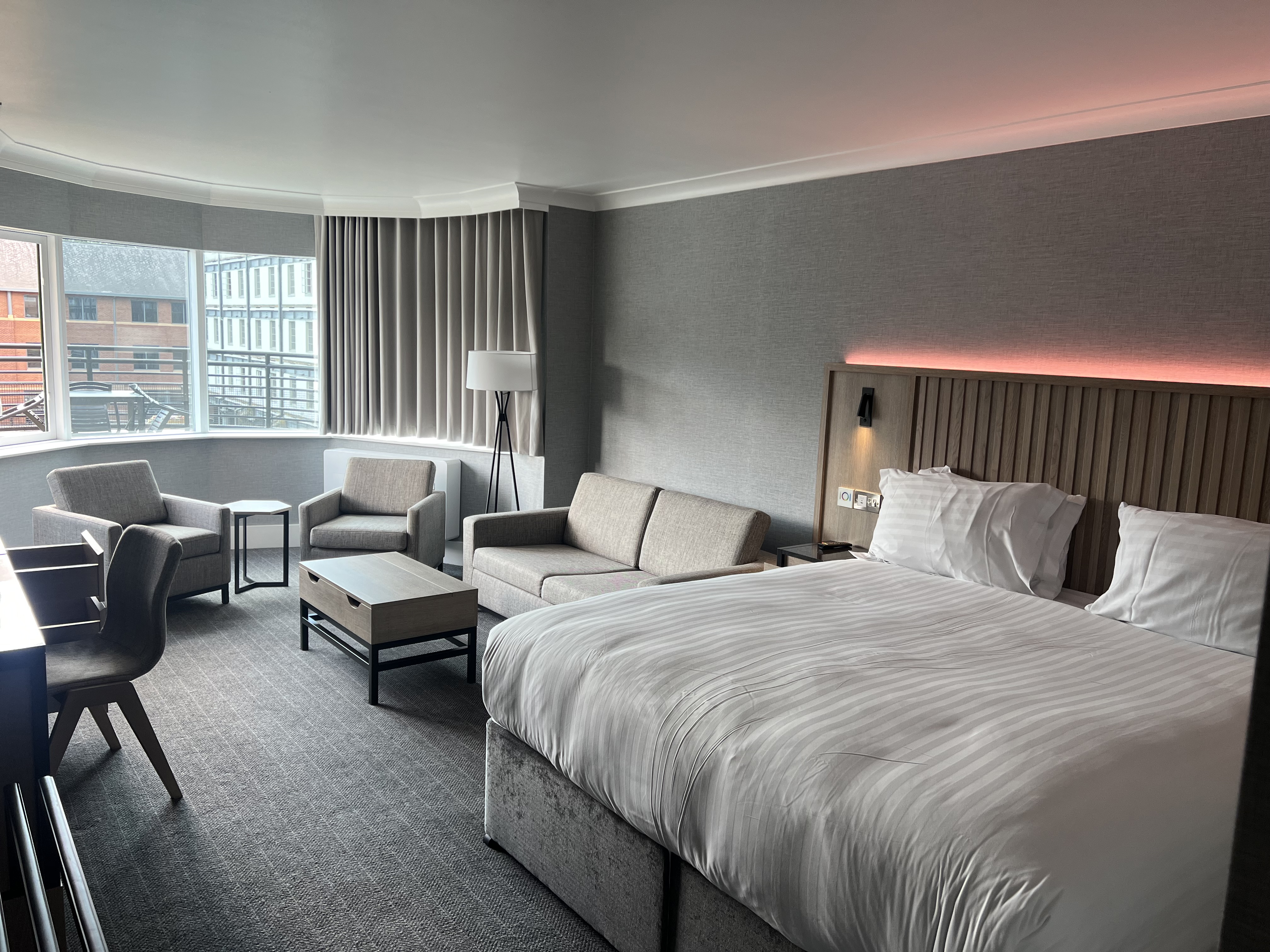 Modern double bedroom with seating area and ambient mood lighting.