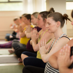 A row of people, sat on the floor, in a yoga class.