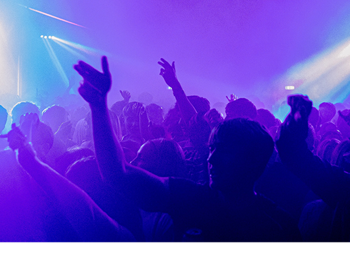 A huge crowd dancing to club music in moody blue lighting.