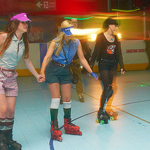 Three people roller skating in a rink. 