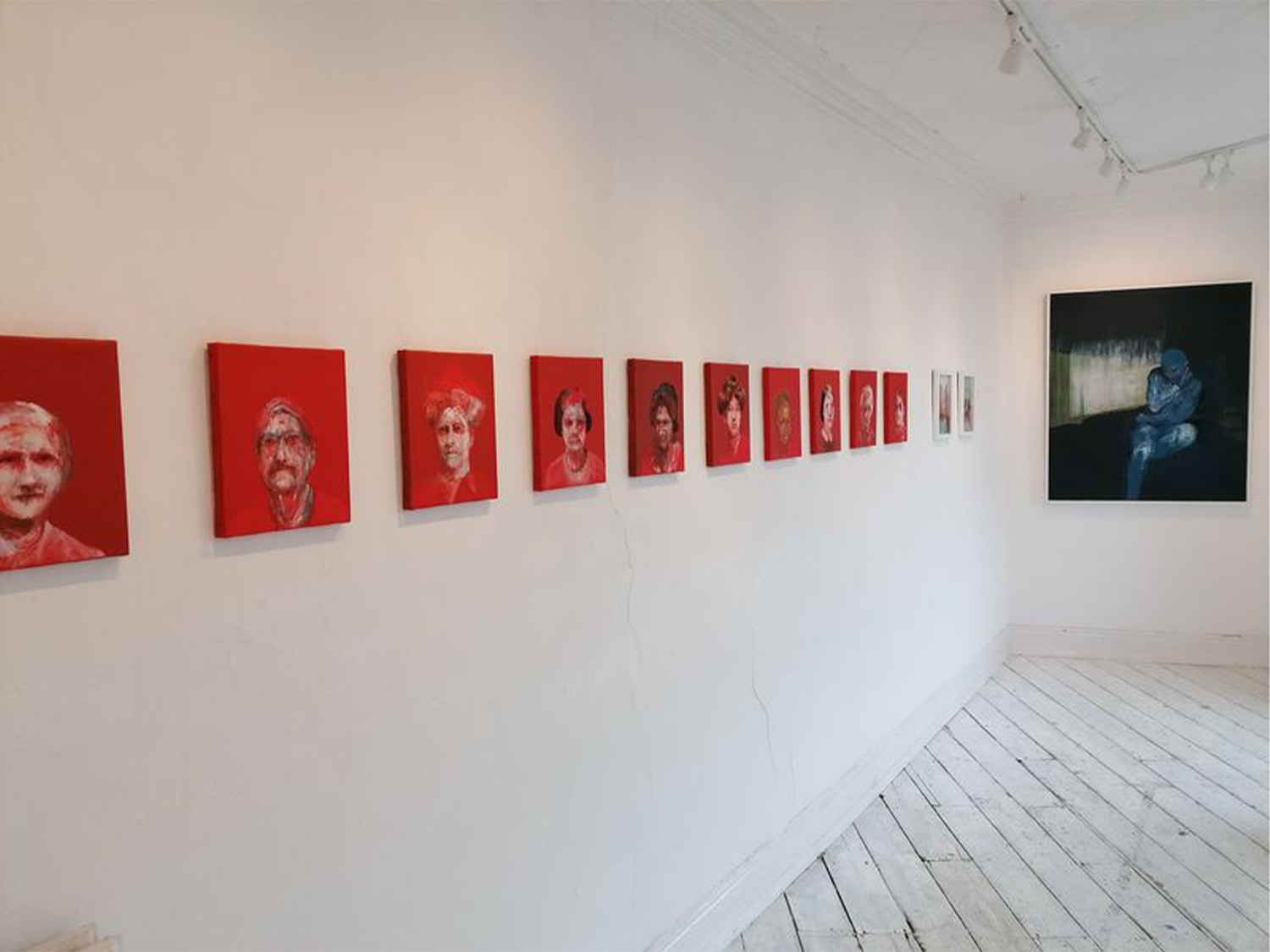 A row of portraits, with striking red backgrounds, at the Cupola Gallery.