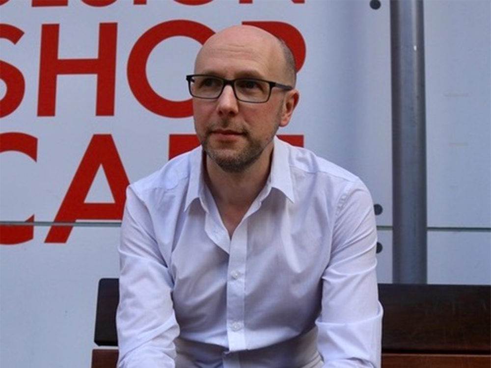 A photo of a man in a white shirt looking off to the side.