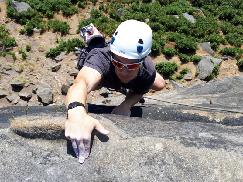 A person climbing up a rock face in the countryside.
