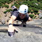 A person climbing up a rock face in the countryside.