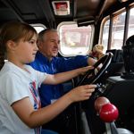 A child and an adult inside a lifeboat in a museum.