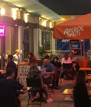 People eating outside, at night, at a cafe.