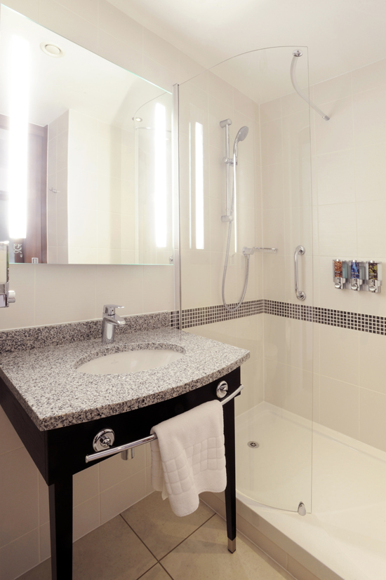 Modern hotel bathroom with shower, sink, and mirror at Hampton by Hilton Sheffield.
