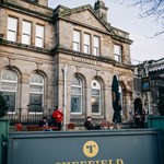 Sheffield Tap exterior outside Sheffield Train Station. A few men are dotted about the outdoor seating area.