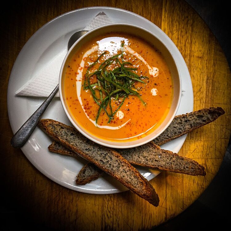 A bowl of soup, with some bresd, photographed from above.