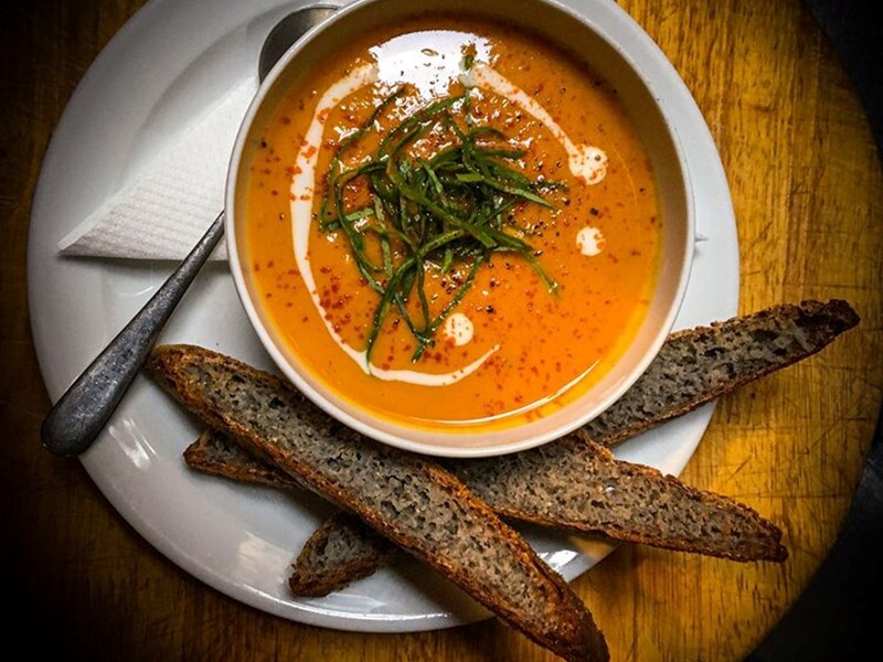 A bowl of soup, with some bresd, photographed from above.