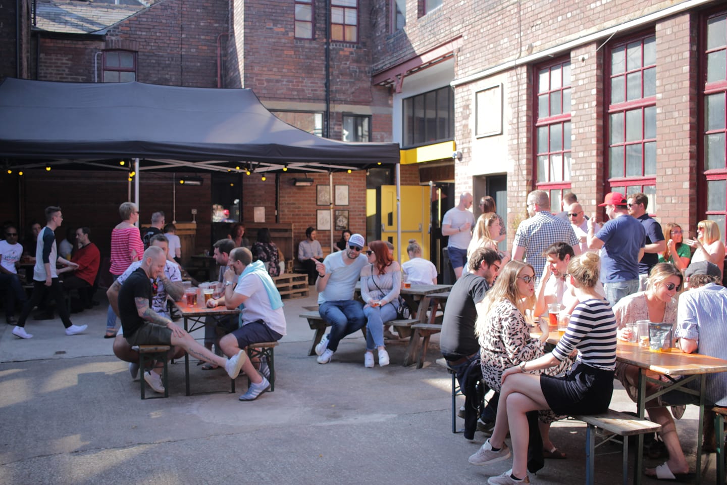 The courtyard at Yellow Arch filled with people standing and sitting at tables.