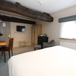 edroom at Mercure Tankersley Manor featuring a bed and a small living area with chairs and a table.