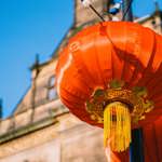 A close up of red lantern hung outside a historic building 