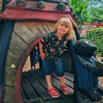 A child playing on a wooden structure in a playground.
