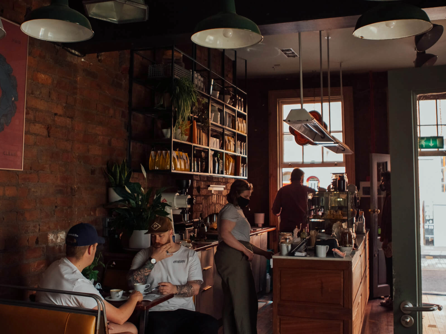 The interior of Mow's Coffee, with staff behind the counter and people drinking coffee and chatting at tables.