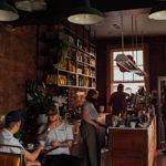 The interior of Mow's Coffee, with staff behind the counter and people drinking coffee and chatting at tables.