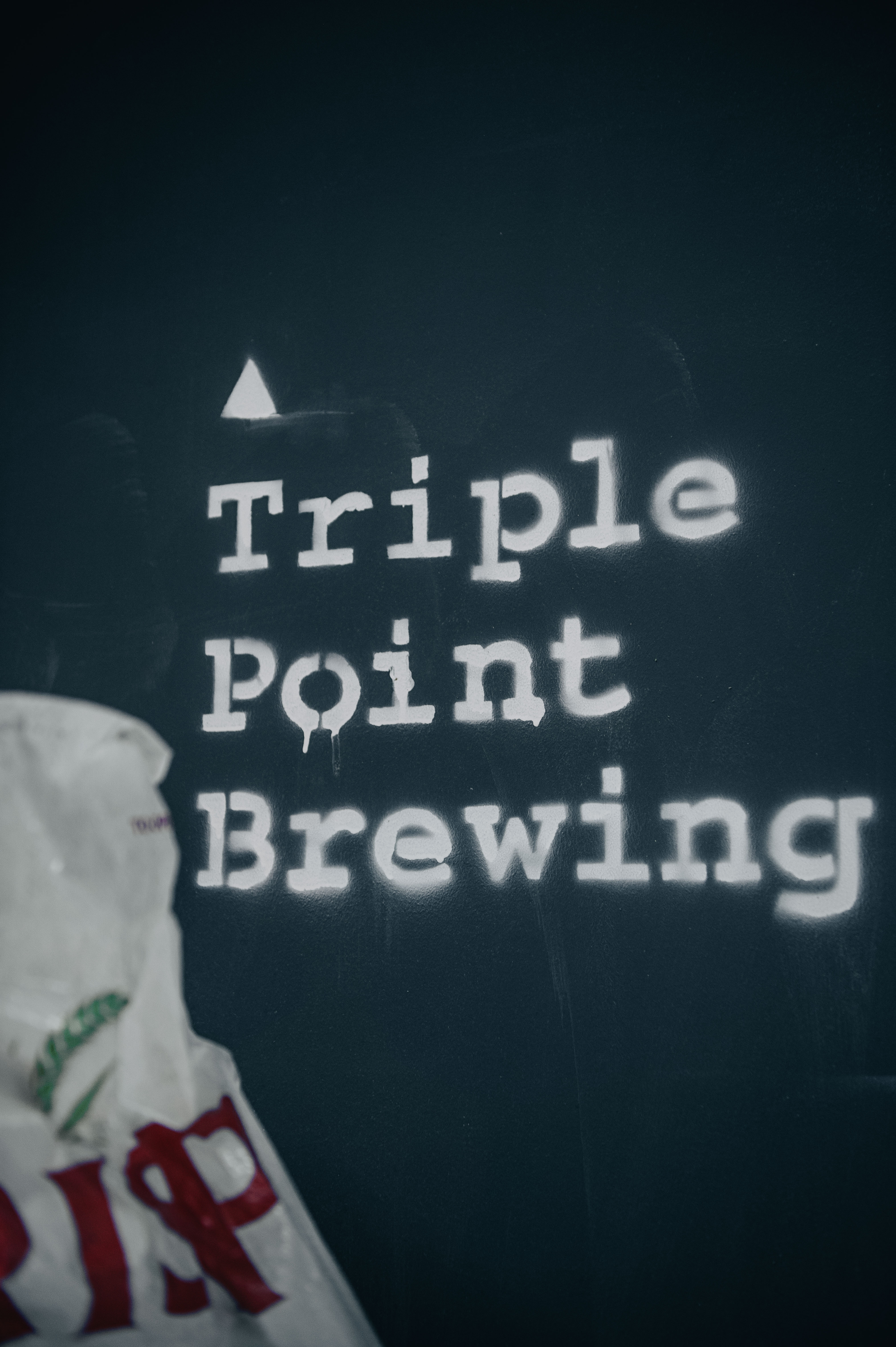 Triple Point Brewery logo in white type-font on black wall.