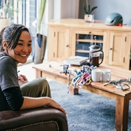 Two women are sat chatting together and drinking coffee in a living room.