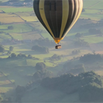 A hot air balloon flies over a scenic landscape.
