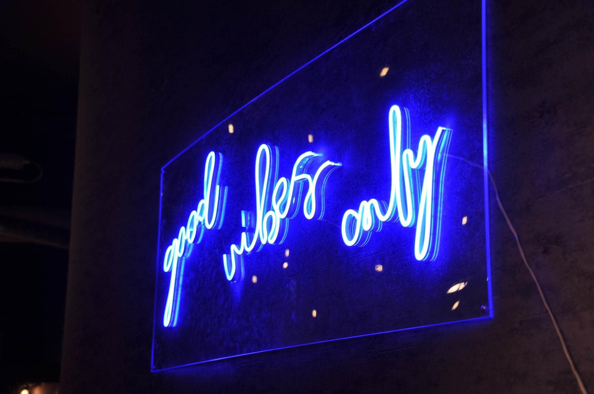 A blue neon sign that reads 'Good vibes only' on the wall at Sheffield Plate.
