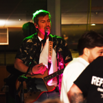 A man is singing and playing a guitar to a crowd.