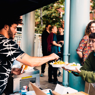 A person buying food at a food stall at an outdoor market.