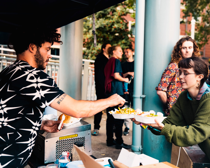 A person buying food at a food stall at an outdoor market.