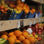 Wooden shelving with baskets full of oranges, apples, bananas and lemons.