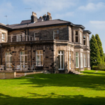 Exterior view of Halifax Hall Hotel surrounded by greenery in Sheffield.
