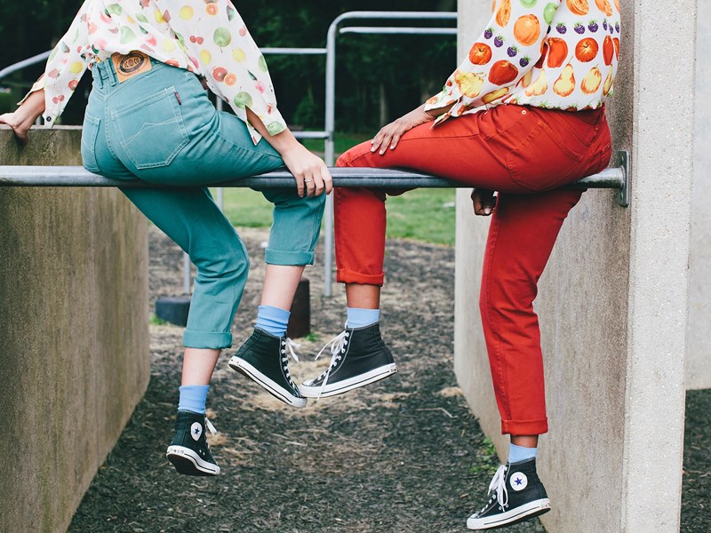 Two people sat om a metal bar between two concrete blocks.