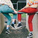 Two people sat om a metal bar between two concrete blocks.