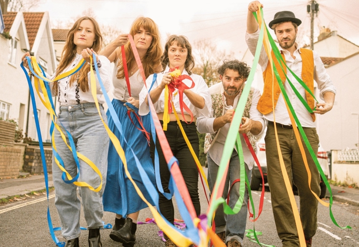 Five people walking down a road, throwing paper streamers.