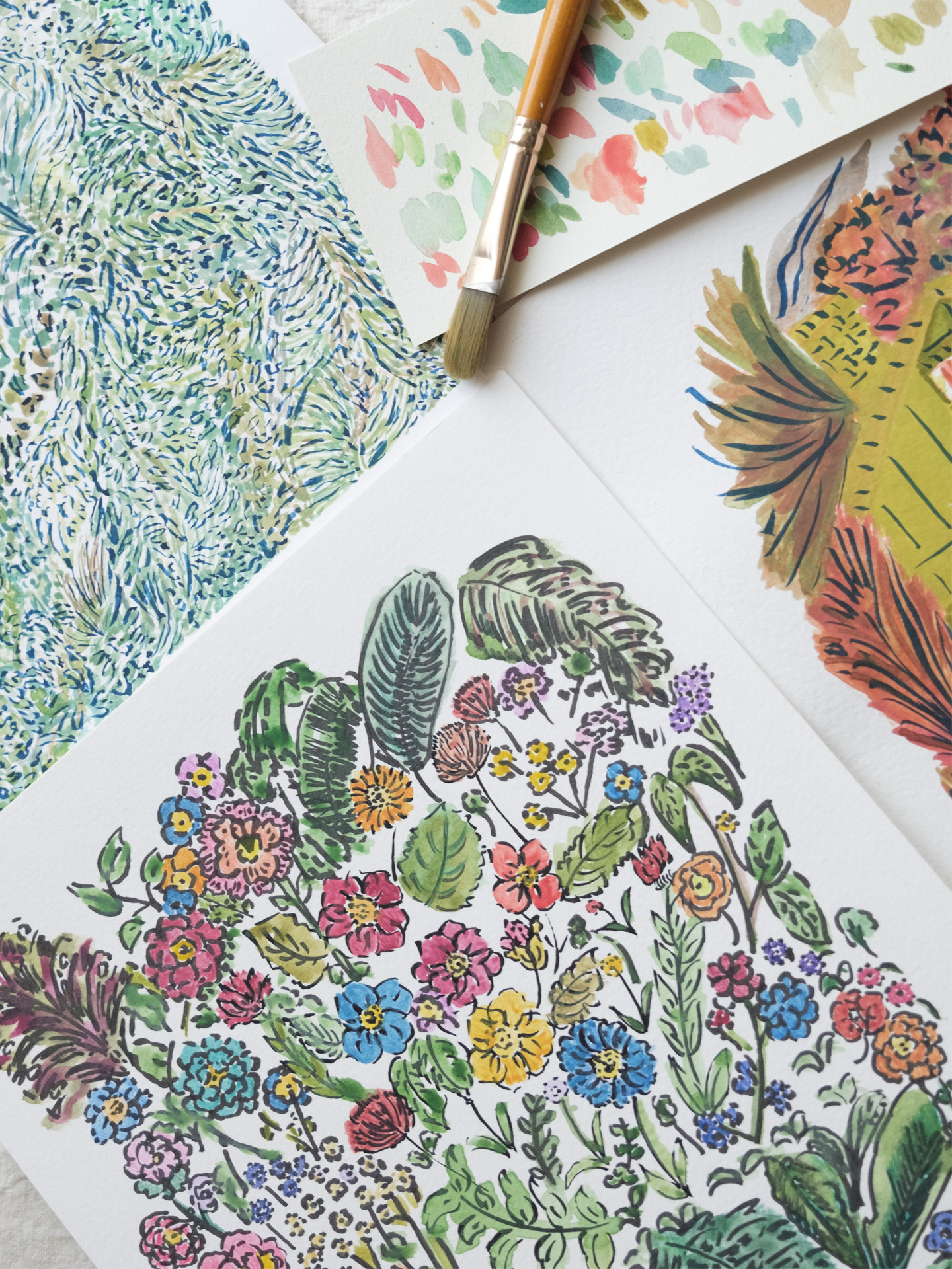 A close-up of colorful botanical illustrations on paper, including vibrant flowers, green leaves, and abstract foliage patterns. A paintbrush and a color swatch card with pastel tones are placed alongside the artwork, suggesting a creative painting process.
