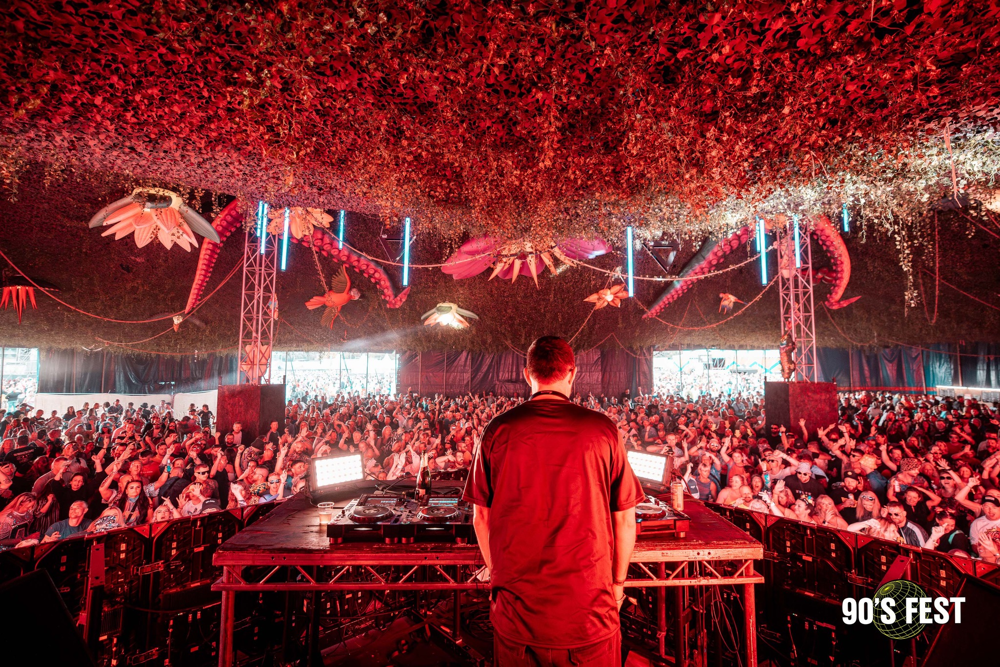 back of a DJ playing to a crowd in a festival tent 