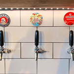 Beer taps set into a white tiled wall at Hymn To Ninkasi
