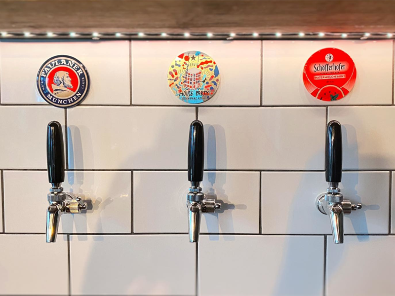 Beer taps set into a white tiled wall at Hymn To Ninkasi