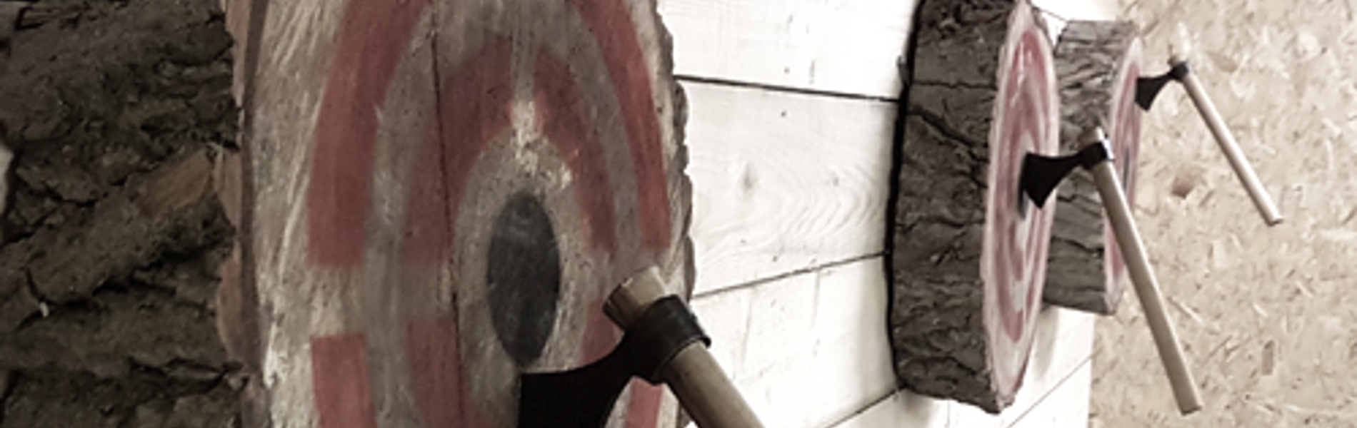 Three wooden targets on a wall, each with a throwing axe in the bullseye.