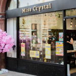 The entrance to Miss Crystal, with a small tree covered in pink blossom to one side.