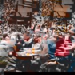 Crowds of people sat on benches drinking beer indoors, with a black and white graffiti wall in the background