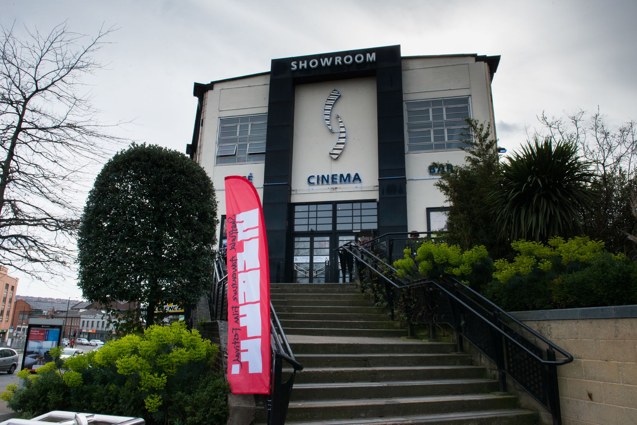 Showroom Cinema in front of grey skies, with a bright pink Sheffield Adventure Film Festival flag to the front left of the building