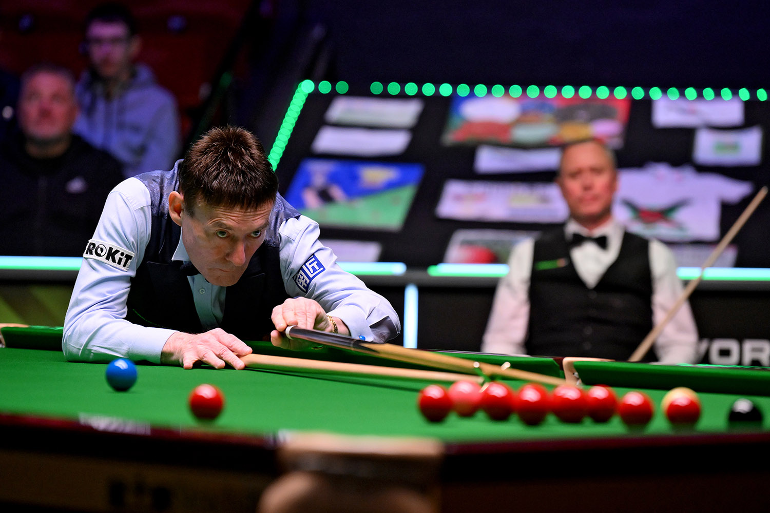 Jimmy White lines up a snooker cue on a table at the World Seniors-Snooker Championship with the crowd in the background 