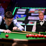Jimmy White lines up a snooker cue on a table at the World Seniors-Snooker Championship with the crowd in the background 