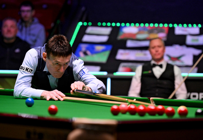 Jimmy White lines up a snooker cue on a table at the World Seniors-Snooker Championship with the crowd in the background 