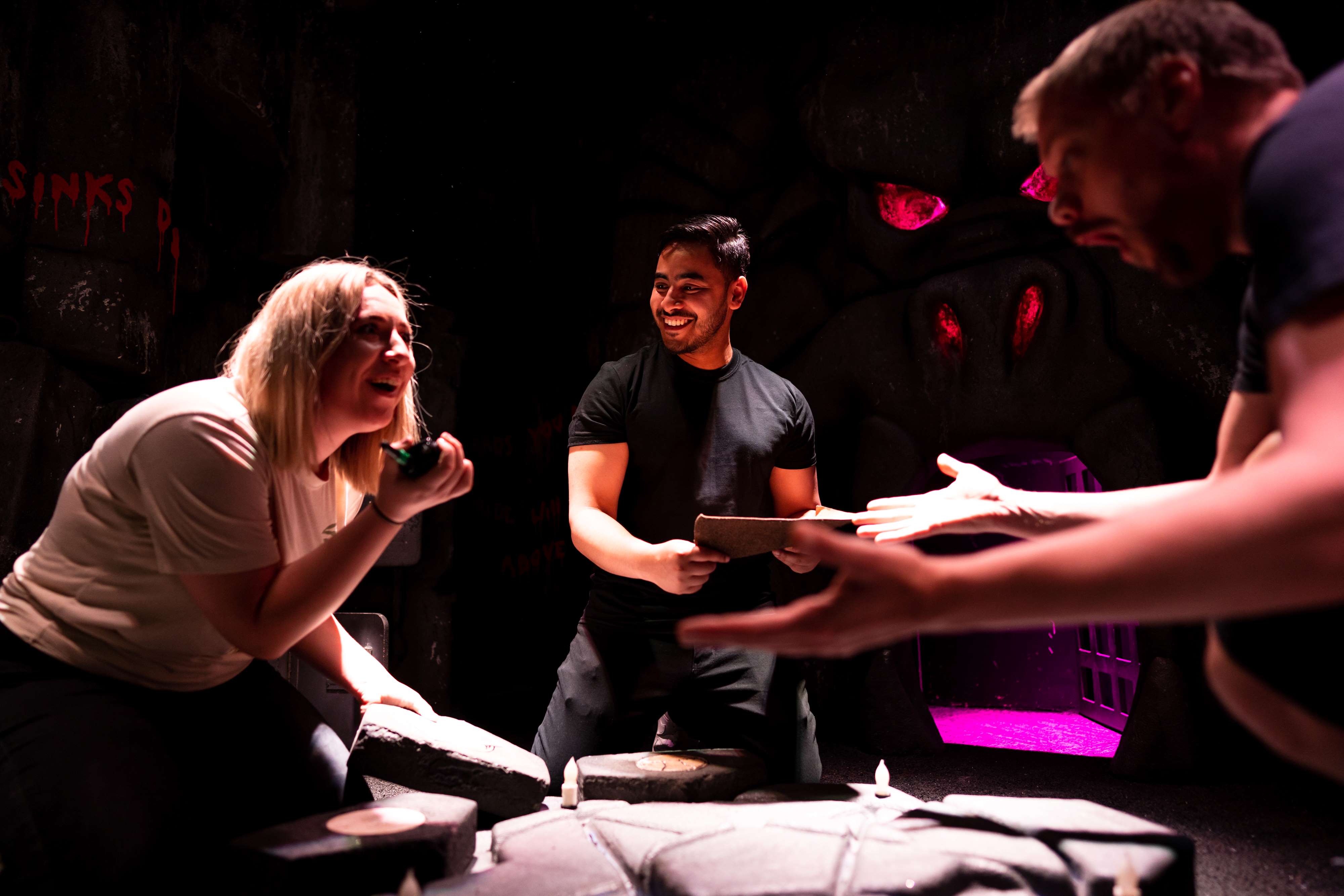 Three people trying to solve a clue in an escape room at The Great Escape Game.