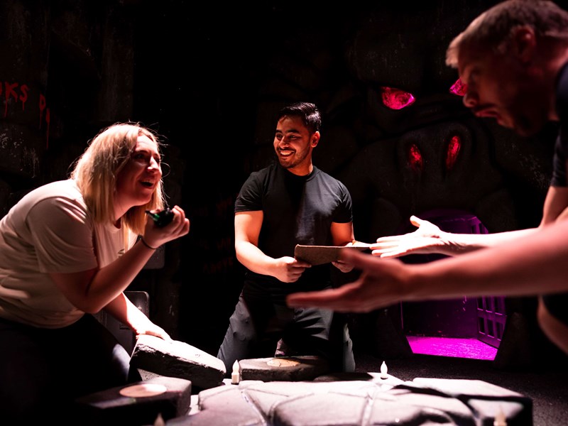 Three people trying to solve a clue in an escape room at The Great Escape Game.