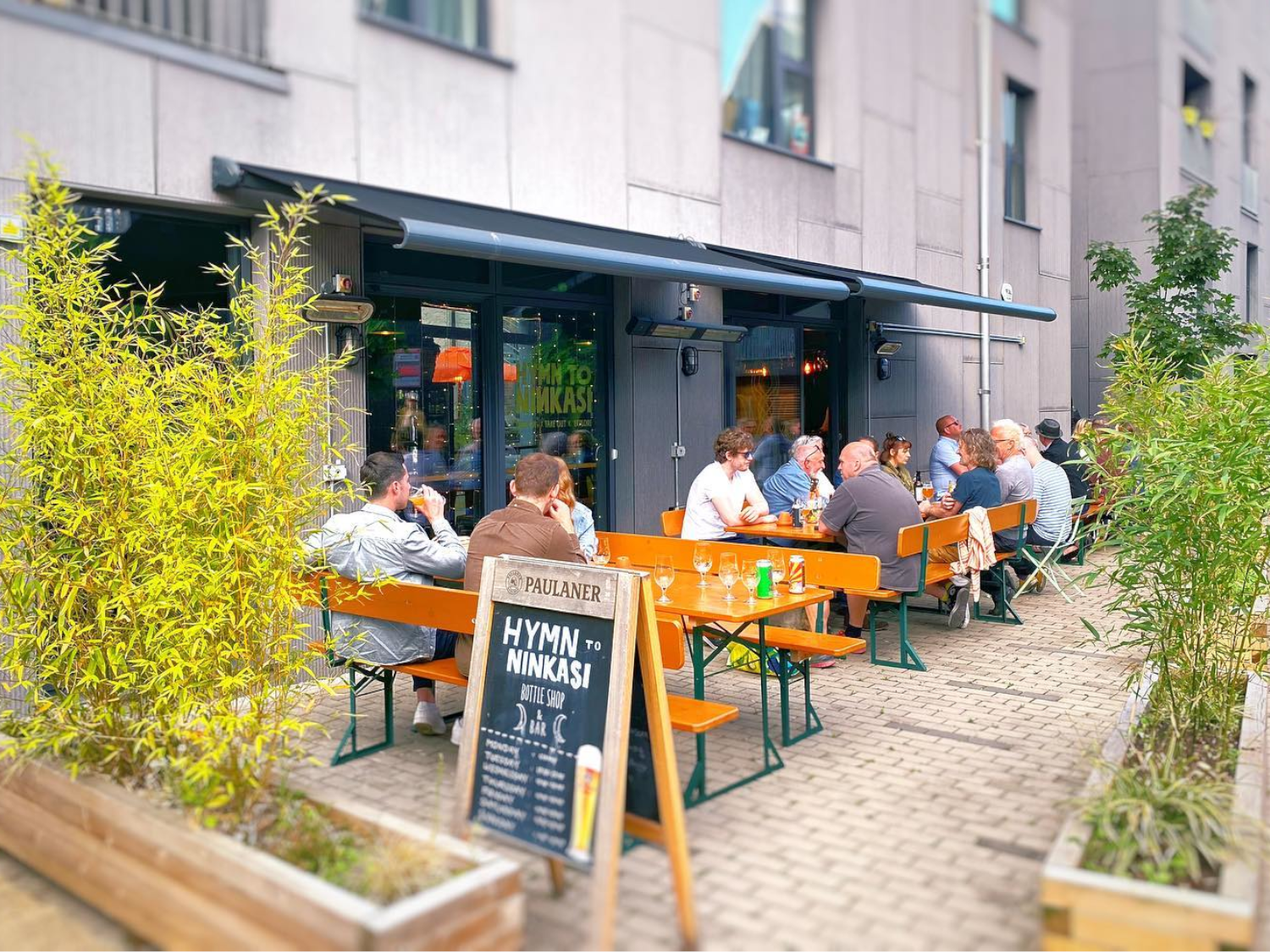 People chatting and drinking at tables outside Hymn To Ninkasi.