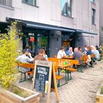 People chatting and drinking at tables outside Hymn To Ninkasi.